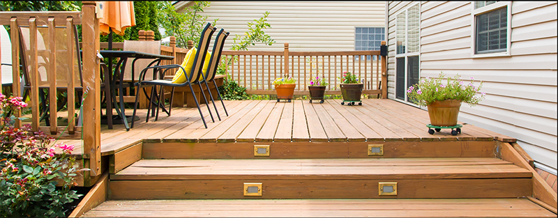 Two steps leading to a deck that has a large entertaining area.