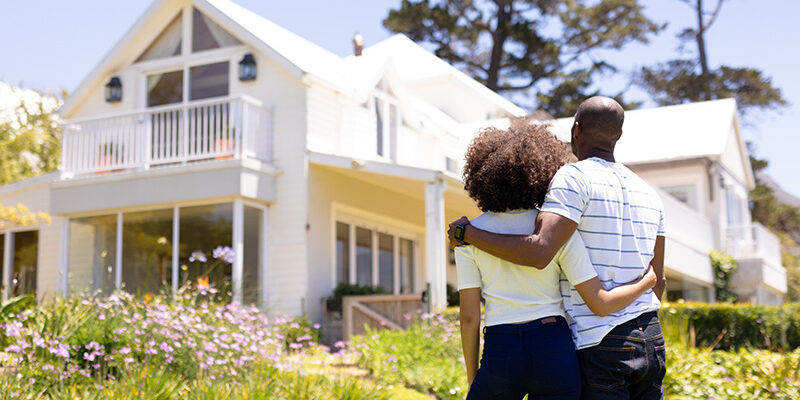 African American couple looking at a white two story home